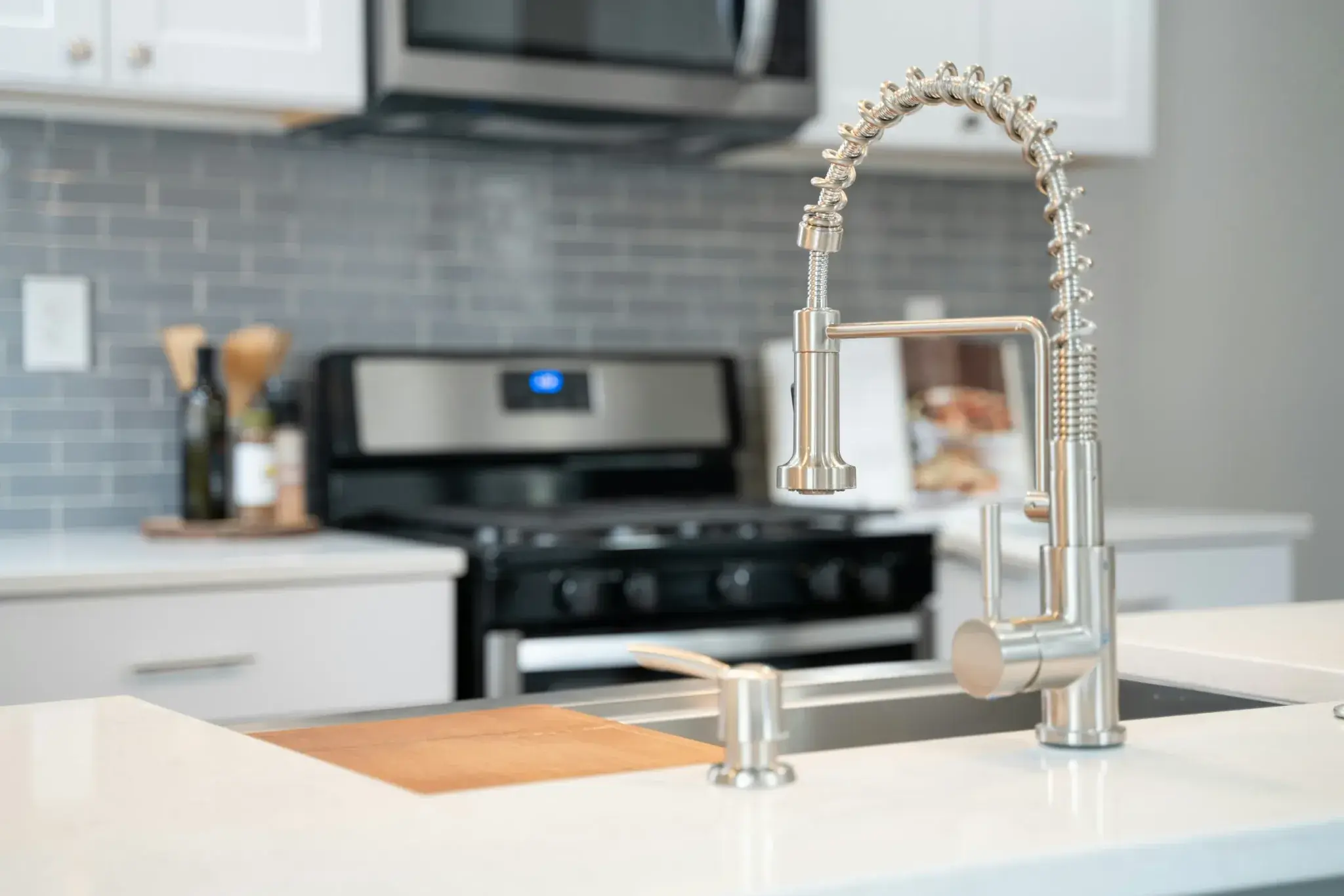A kitchen sink and tap in the foreground with a cooker behind